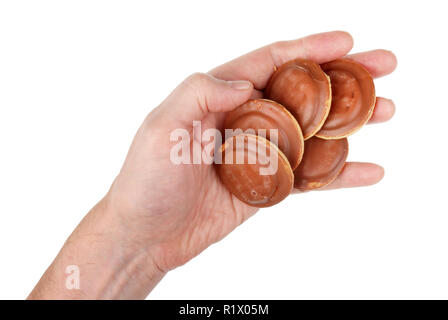 L'ancienne main de l'homme détient un soft brown donuts avec lustre de chocolat. Gros plan studio isolated on white Banque D'Images