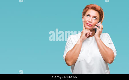 Atrractive young redhead Woman talking on smartphone sur fond isolé visage sérieux de penser à question, idée très confus Banque D'Images