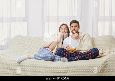Un jeune couple assis sur le canapé à regarder un plat intéressant . Banque D'Images