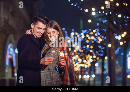 Un jeune couple laughing with sparklers dans les mains d'une ville st Banque D'Images