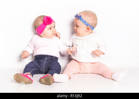 Deux bébés filles assis sur marbre sur mur blanc Banque D'Images