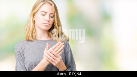 Belle jeune femme portant des T-shirt oversize sur fond isolés souffrant de douleur sur les mains et les doigts, l'inflammation de l'arthrite Banque D'Images