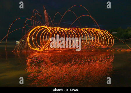 Reflet de l'incendie de l'étincelle de turbulence de la laine d'acier avec une exposition longue motion vitesse résumé au lever du soleil dans la mer Banque D'Images