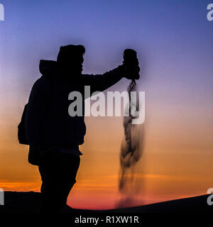Man pouring sable par les dunes de sable au coucher du soleil en CA Banque D'Images