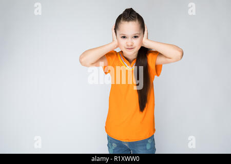 Fille sur un fond gris mit ses mains sur ses oreilles. Banque D'Images