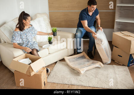 Jeune couple déménagement dans de nouvelles boîtes de carton et déballage accueil.Presque fini le déménagement. Banque D'Images