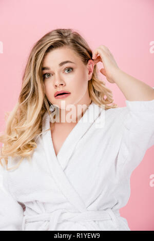 Portrait of young woman in bathrobe surdimensionnée looking at camera isolé sur pink Banque D'Images