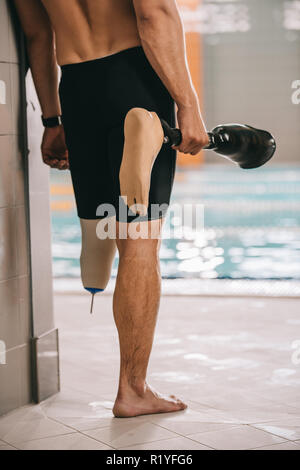 Cropped shot de sportif de la piscine, piscine intérieure et tenant sa jambe artificielle Banque D'Images