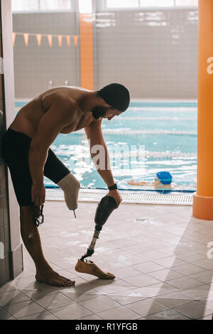 Jeune nageuse athlétique au bord de l'article piscine intérieure et décoller la jambe artificielle Banque D'Images