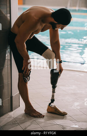 Beau nageur au bord de l'article piscine intérieure et décoller la jambe artificielle Banque D'Images