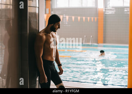 Beau nageur avec jambe artificielle au bord de l'article piscine intérieure Banque D'Images