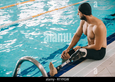 Beau jeune nageuse avec jambe artificielle assis sur de la piscine intérieure chauffée Banque D'Images