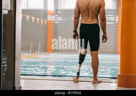 Cropped shot de sportif avec jambe artificielle debout devant une piscine intérieure Banque D'Images