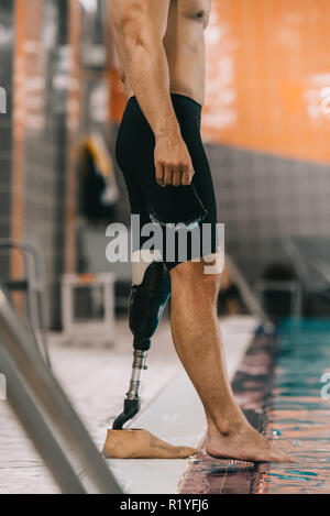 Cropped shot du nageur avec jambe artificielle à bord de piscine intérieure et contrôler la température de l'eau Banque D'Images