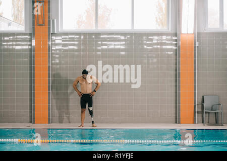 La jeune sportsman avec jambe artificielle à bord de piscine intérieure Banque D'Images