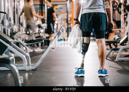 Cropped shot de sportif avec jambe artificielle debout à une salle de sport et une serviette holding Banque D'Images