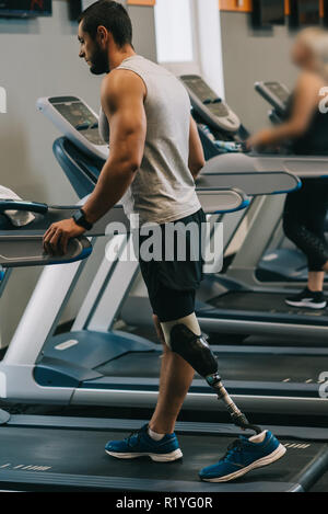 Beau jeune sportsman avec jambe artificielle marche sur treadmilsl at gym Banque D'Images