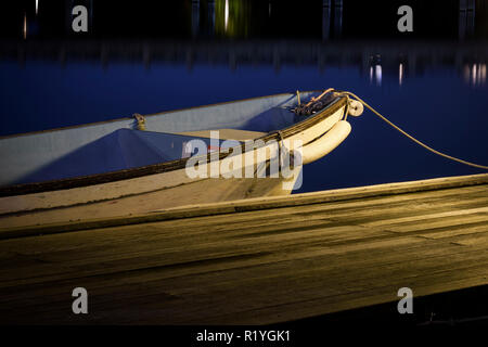 Un petit bateau en bois garé au quai ou à une jetée à la nuit. La photographie de nuit avec lisse bleu eaux. Banque D'Images