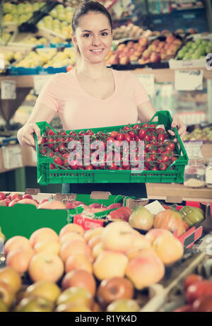 Portrait de l'assistant en magasin avec caisse remplie de tomates fraîches Banque D'Images