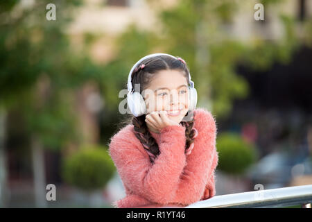 Cool drôle fille élégant est à l'écoute de la musique et penser à positivité. Girl sur le pont avec le casque. Influence de la musique tranquille. Nice girl in pink sweater profitant de chanson.