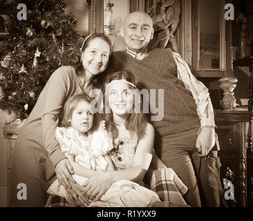 Imitation de vieille photo de famille heureuse de trois générations qui pose pour portrait de Noël Banque D'Images