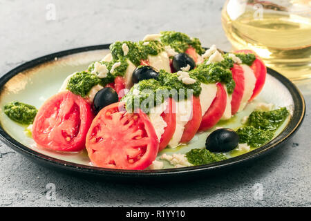 Salade caprese tomate et mozzarella et pesto aux olives de table gris servi la carafe avec de l'huile d'olive alimentaire italien apéritif Banque D'Images