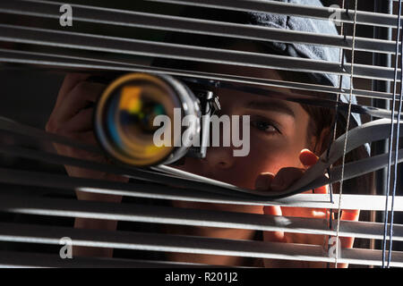 Jeune femme photographe Paparazzi capture d'une photo d'un air suspicieux autour d'une jalousie tout en utilisant un appareil photo Banque D'Images