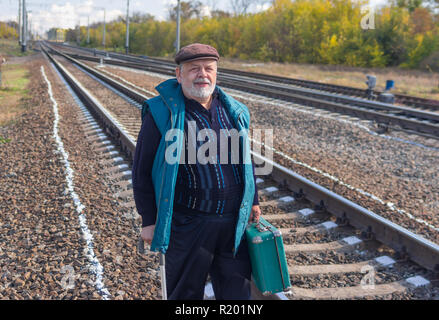 Bearded man near Railway et la tenue d'une vieille valise verte Banque D'Images