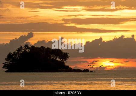 Incroyable coucher du soleil derrière une petite île, vu de la plage de Naiyang à Phuket, Thaïlande Banque D'Images