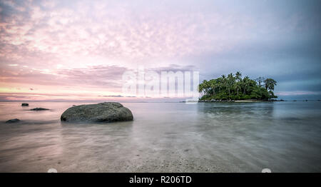 Incroyable coucher du soleil derrière une petite île, vu de la plage de Naiyang à Phuket, Thaïlande Banque D'Images