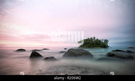 Incroyable coucher du soleil derrière une petite île, vu de la plage de Naiyang à Phuket, Thaïlande Banque D'Images