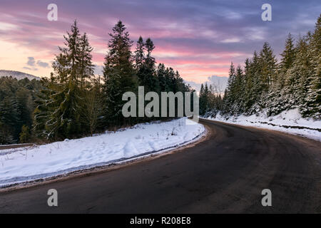 En serpentine à la forêt de sapins enneigés au crépuscule. beaux paysages d'hiver dans les montagnes avec de magnifiques purple sky Banque D'Images
