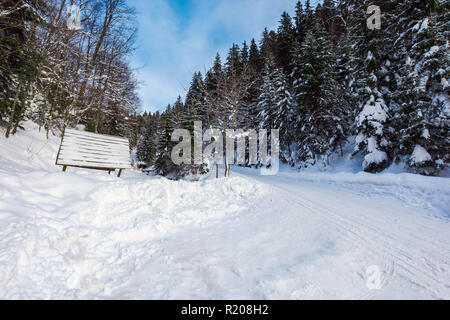 La neige a couvert route qui serpente à travers la forêt en montée aventures d'hiver magnifique. Banque D'Images