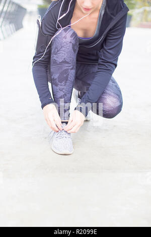 Voir à attacher les lacets femme sportive sur des chaussures de course avant la pratique Banque D'Images