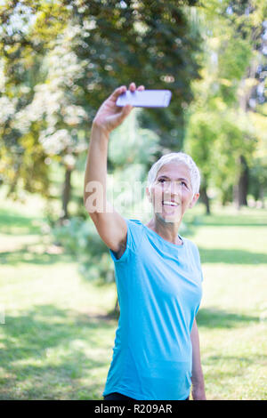 Sporty woman with mobile phone selfies prise dans le parc Banque D'Images