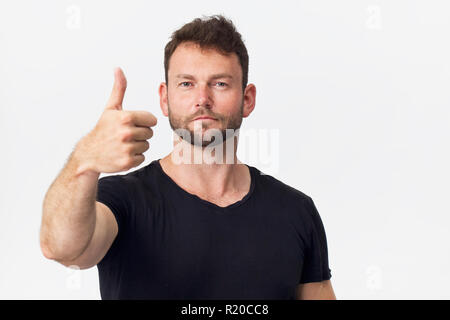 Des hommes souriant avec aspect attrayant, porter t-shirt noir, posant contre un mur blanc vide Banque D'Images
