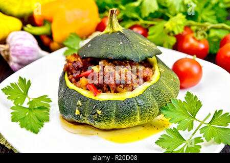 Vert courge farcie de viande, les tomates et les poivrons dans le plat, l'ail et le persil sur un fond de bois Banque D'Images