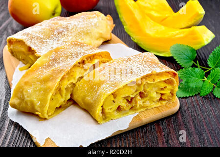 Citrouille Strudel aux pommes et aux raisins secs sur papier, de menthe, de fruits et légumes sur le fond de panneaux de bois Banque D'Images