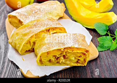 Citrouille Strudel aux pommes et aux raisins secs sur papier, les fruits et légumes sur une planche en bois foncé Banque D'Images