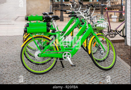 Des vélos de location verte avec des paniers en stationnement sur une rue pavée, à Berlin, Allemagne, papier peint. Banque D'Images