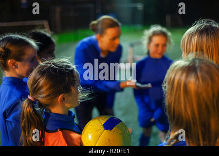 Les joueurs de soccer Girl listening to coach dans huddle Banque D'Images