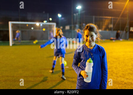 Portrait of smiling girl soccer player l'eau potable sur la nuit sur le terrain Banque D'Images