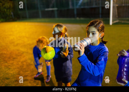 Girl soccer player en faisant une pause sur l'eau potable, domaine la nuit Banque D'Images