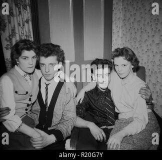 Années 1950, les romantiques, une paire de jeunes couples courtiser étroitement assis ensemble dans une chambre à l'avant, England, UK. Banque D'Images