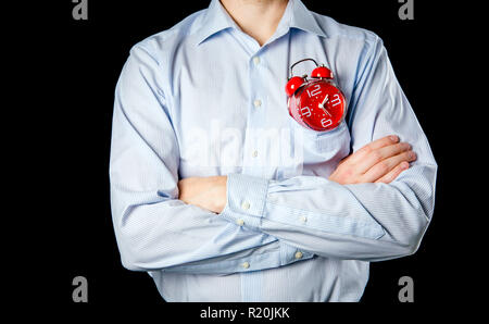 Mâle adulte portant chemise formelle et mains croisées holding big red vintage réveil. Concept de temps. Banque D'Images