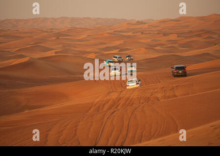 Aventure hors-route avec SUV roulant en désert d'Arabie au coucher du soleil. Véhicule tout terrain à travers bashing dunes de sable dans le désert de Dubaï. Animations traditionnelles Banque D'Images