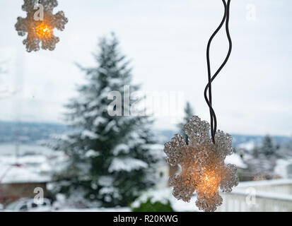 Les lumières de Noël accroché à la fenêtre avec vue sur les arbres enneigés Banque D'Images