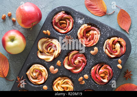 Le bac d'apple en feuilleté au four roses sur fond texturé gris avec les feuilles d'automne et pommes rouges Banque D'Images