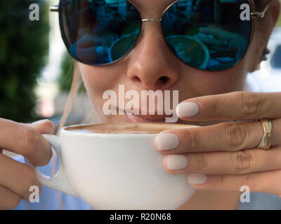 Jeune femme portant des lunettes de profiter de l'extérieur du café, cropped portrait Banque D'Images