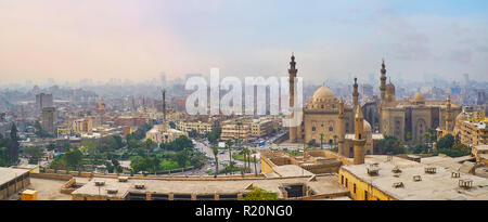 La silhouette de foggy vieux Caire derrière Al Riai" (Royal), les mosquées Sultan Hassan et végétation luxuriante de Salah El-Deen Square, l'Égypte. Banque D'Images
